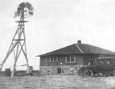 vintage photo of the original homestead with an old car and windmill.